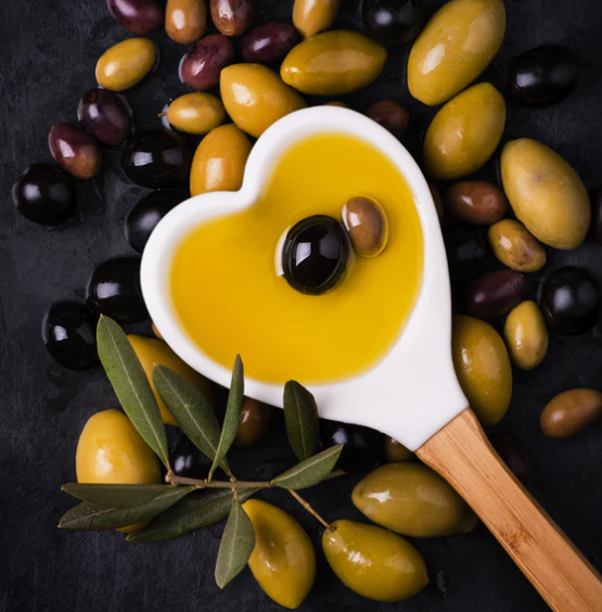 olive oil in a heart shaped sppon laying on a bed of olives
