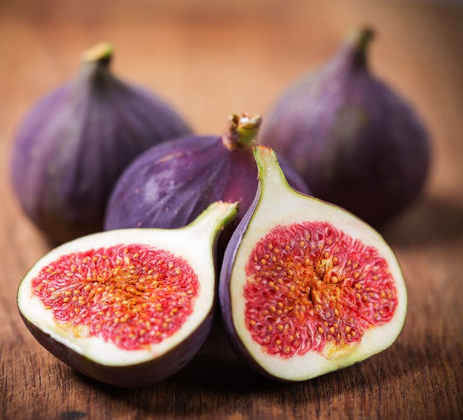 4 figs sitting on a table, one is cut in half